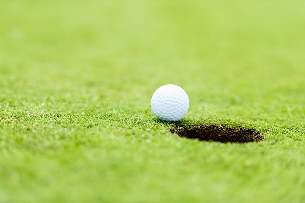 Golf ball at the course going into a hole